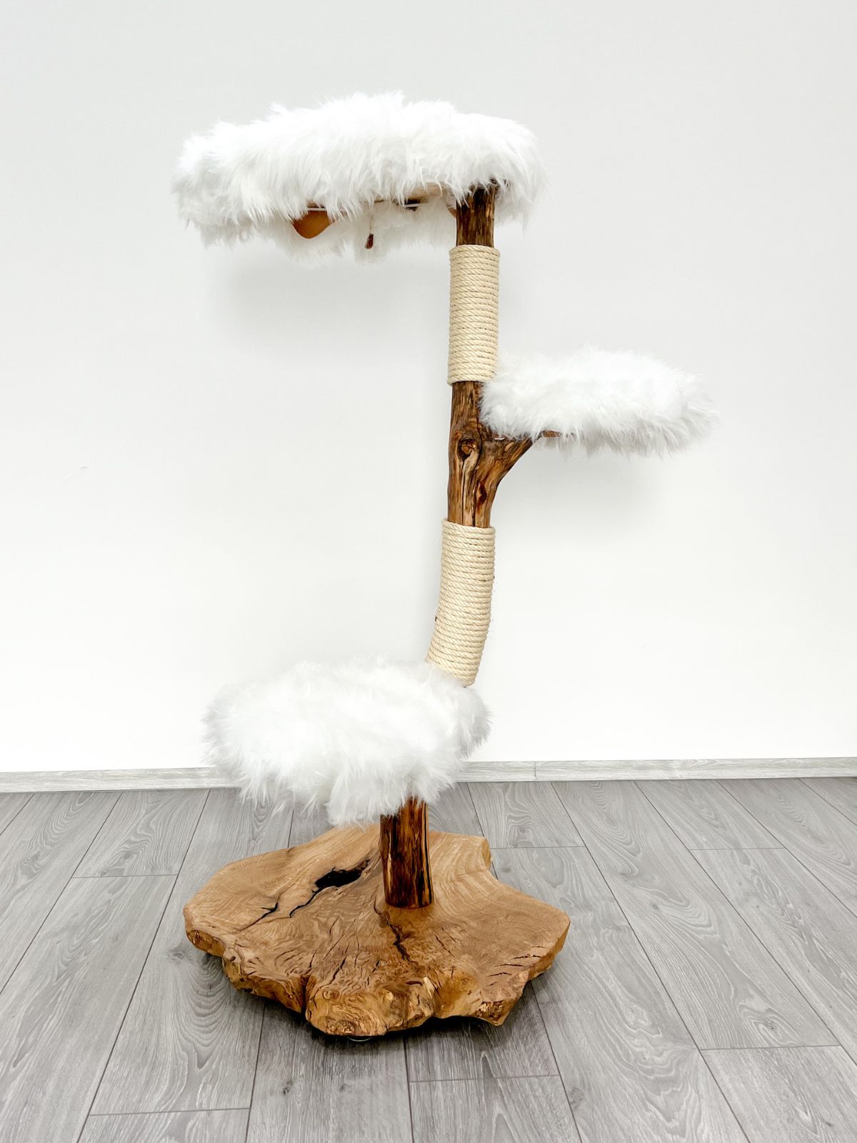 Ein Naturkratzbaum mit weißen Fellbezügen